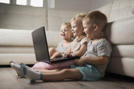 little-sibbling-sitting-floor-looking-laptop